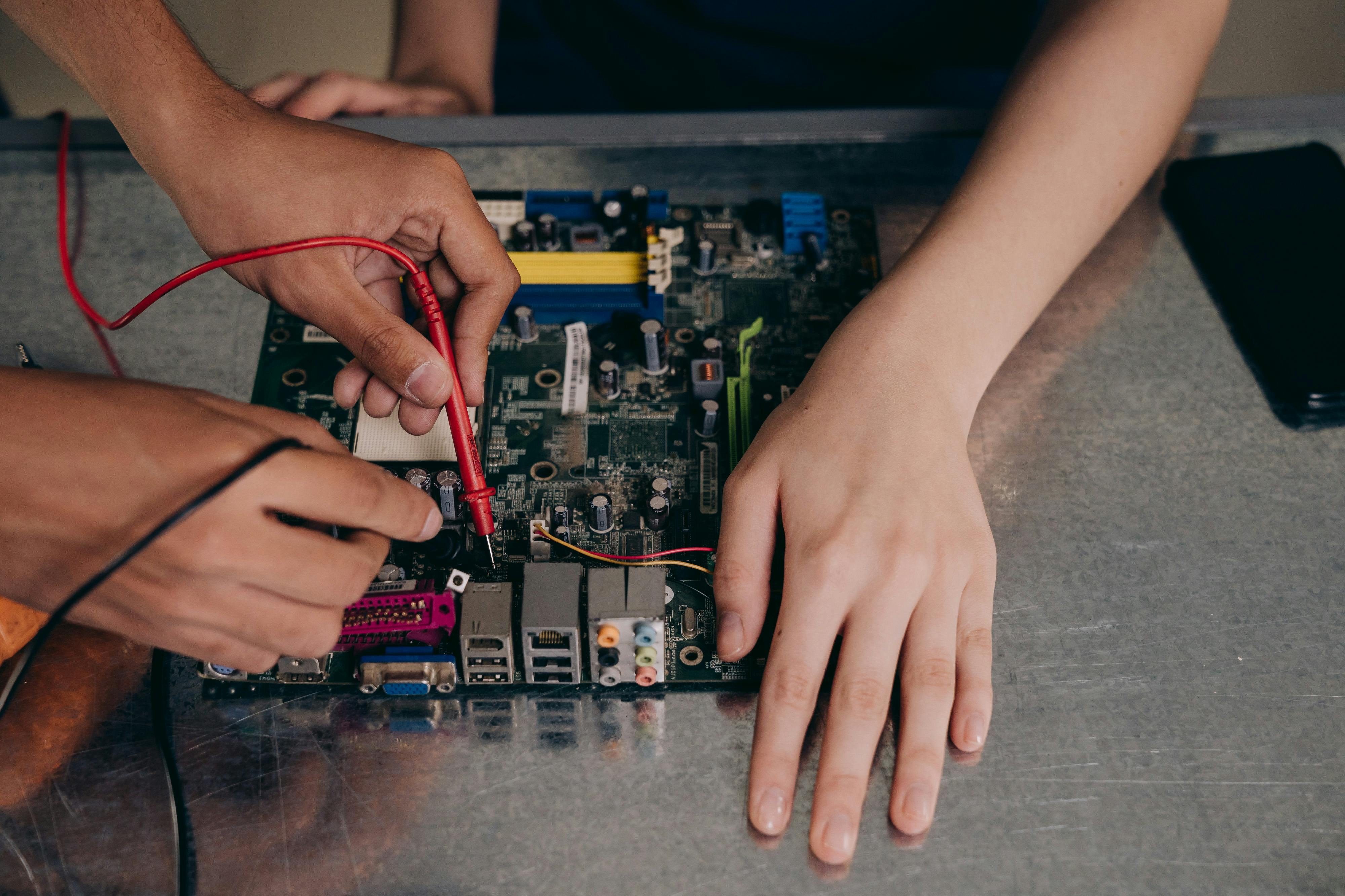 Hands testing and inspecting internal components of a school-issued computer during device repair and maintenance.