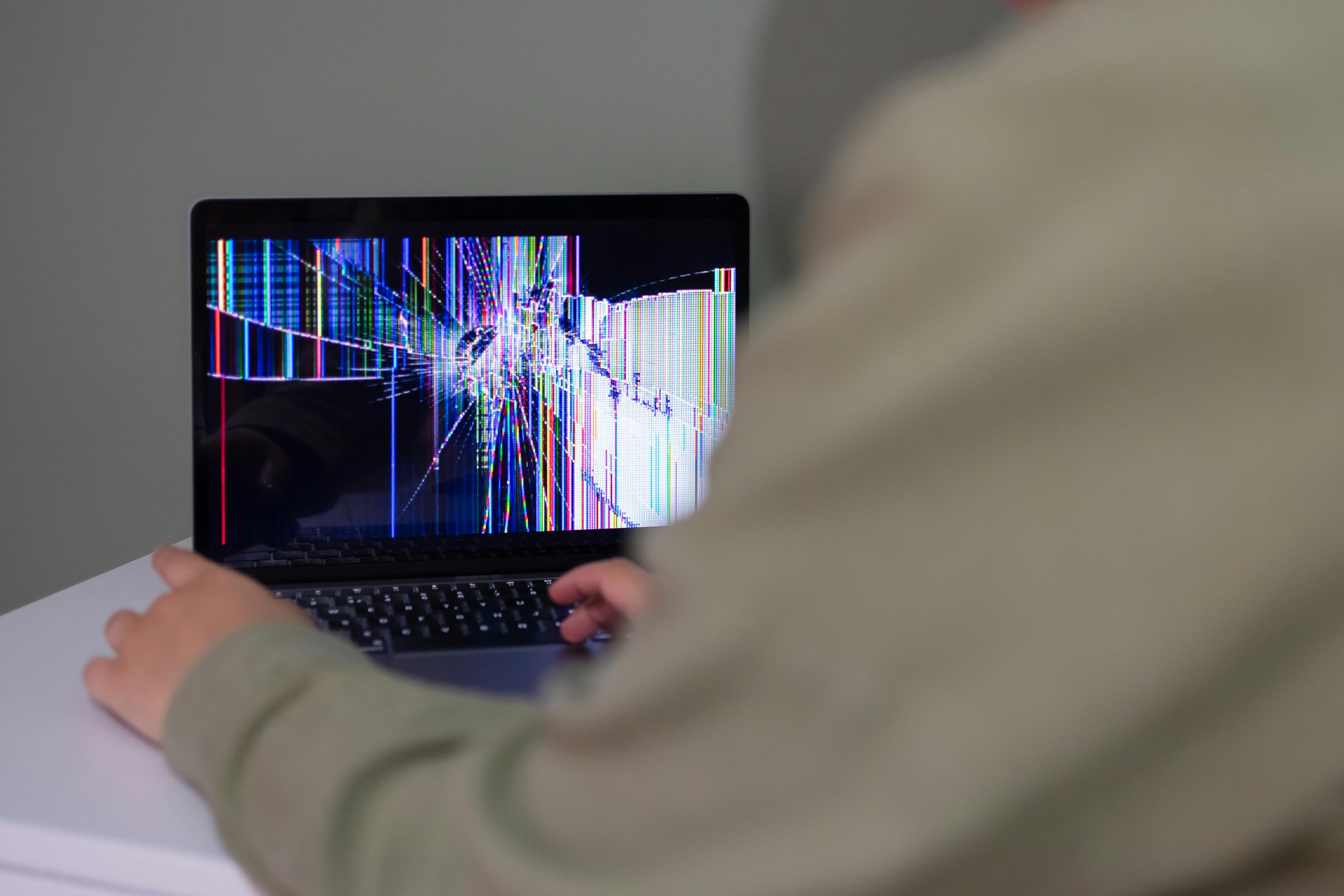 Broken laptop screen with visible cracks and display damage, illustrating a school device that may need repair or replacement.